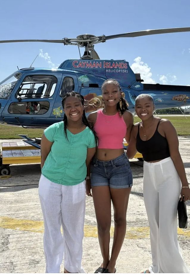 Three friends smiling in front of the helicopter